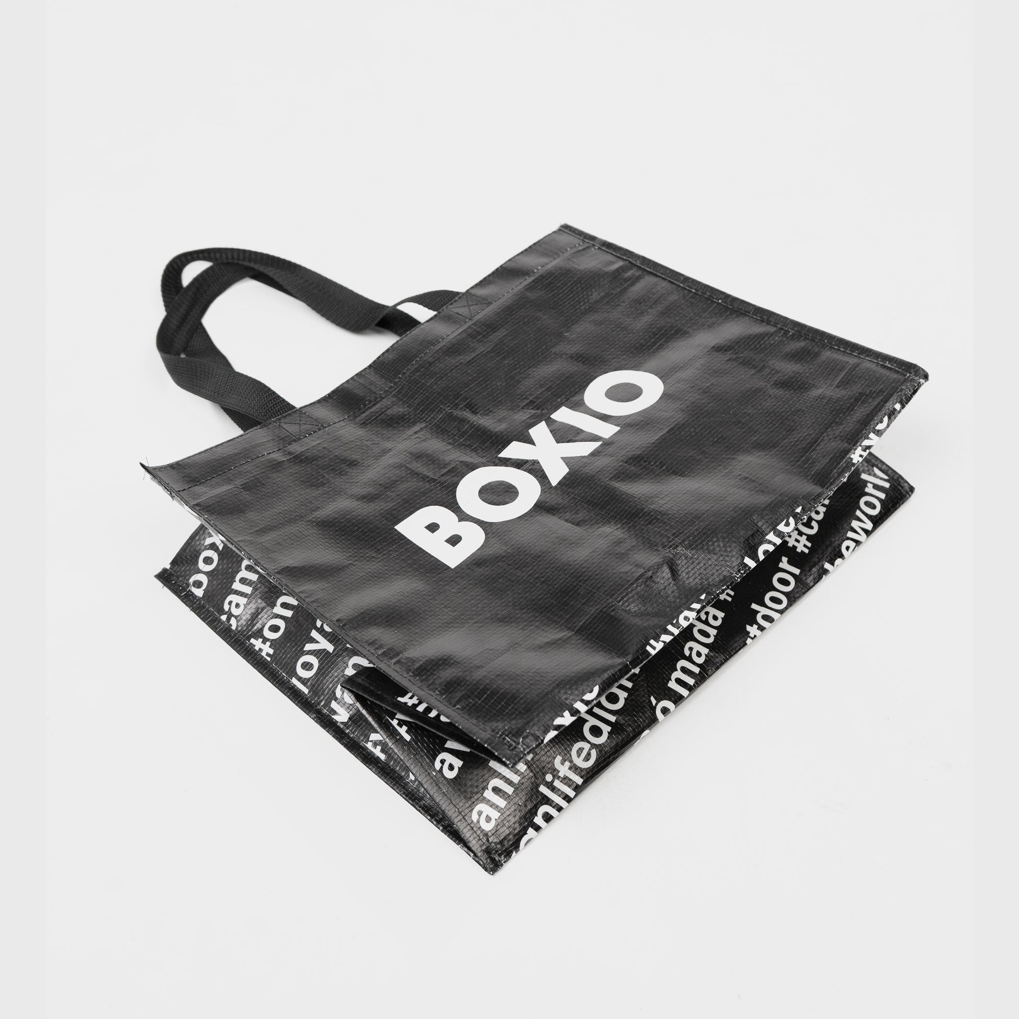 Schwarze Tragetasche mit dem Schriftzug "BOXIO" und wiederverwendbarem Innenleben mit Grafiken und Text.