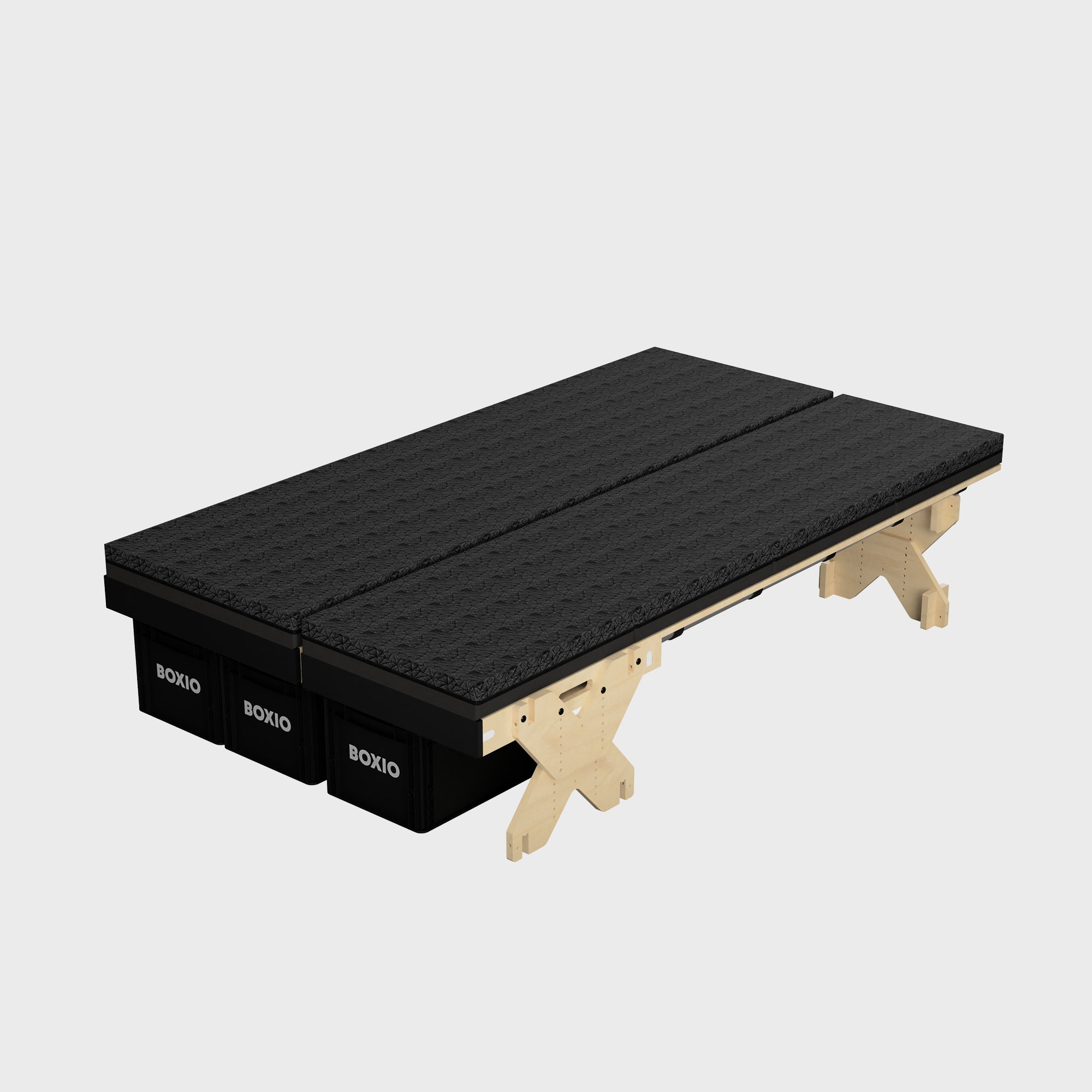 Modulares Bettgestell mit schwarzen Matratzen auf Holzunterbau und schwarzen Boxio-Lagerkisten.