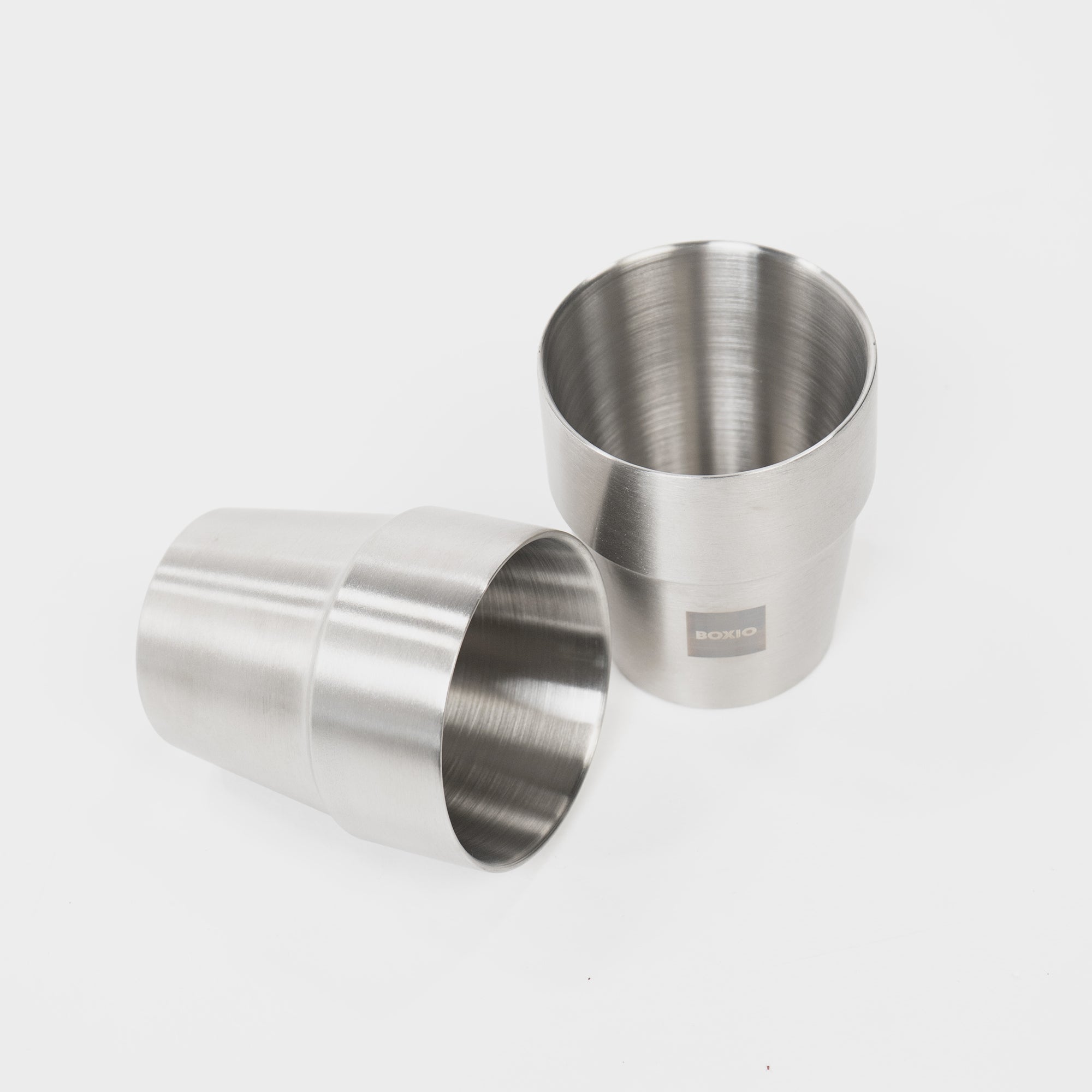 Zwei elegante Edelstahlbecher mit mattem Finish, einer stehend und einer liegend.