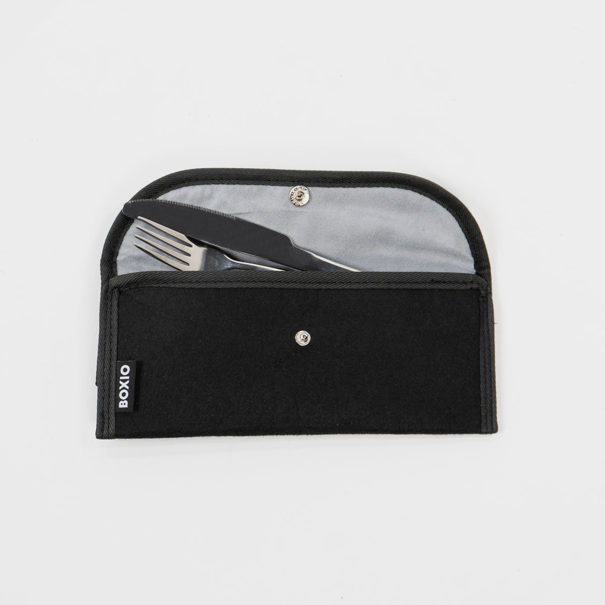 Schwarze Tasche mit Besteck, bestehend aus Messer und Gabel, auf grauem Hintergrund. Trendiges, nachhaltiges Design.