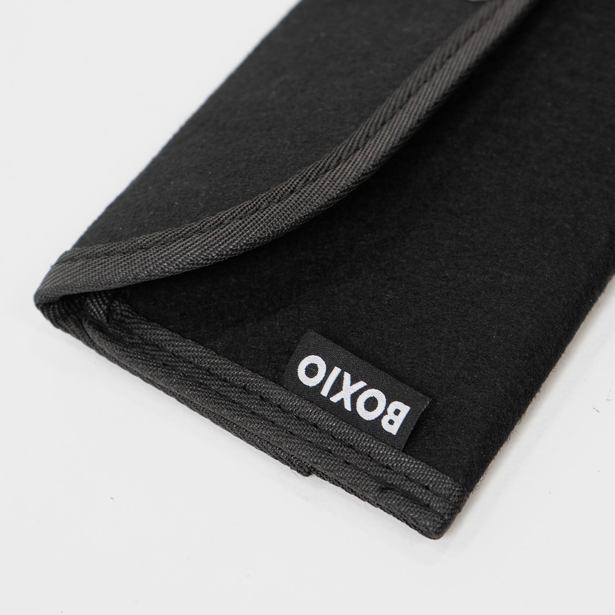 Schwarze, gefaltete Tasche aus Filz mit einer grauen Kante und dem Label „boxito“ an der Seite.
