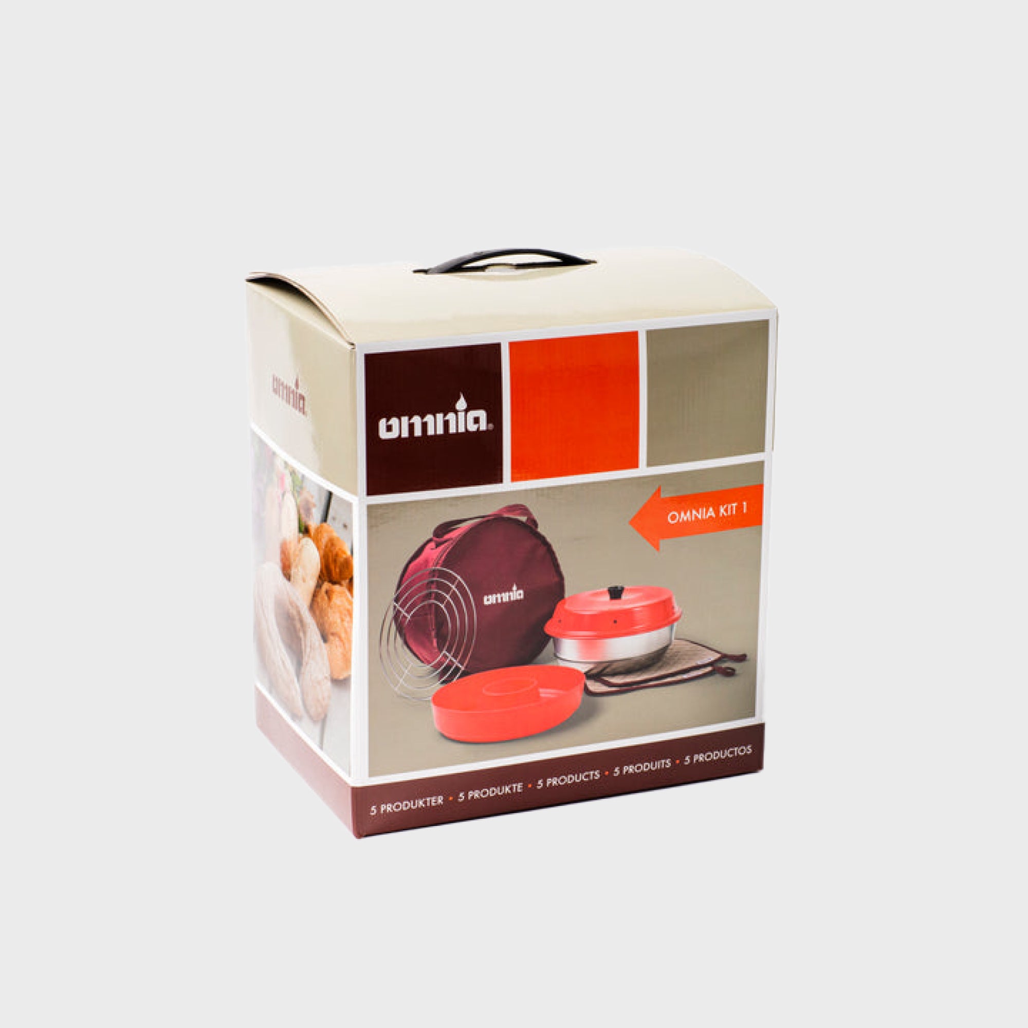 Verpackung des Omnia Kit 1 mit rotem Kochgerät und Zubehör, abgebildet mit frischen Brötchen.