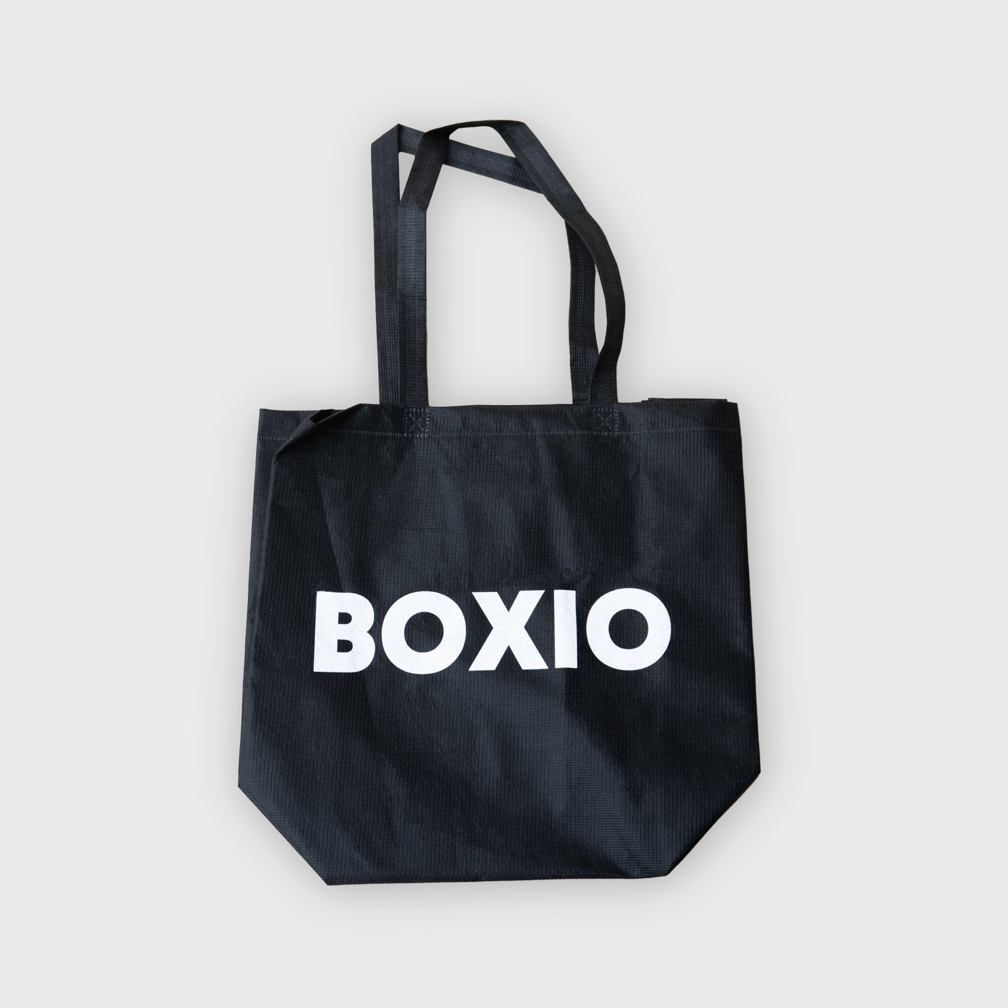 Schwarze Tragetasche aus Stoff mit dem Schriftzug "BOXIO" in großen weißen Buchstaben.