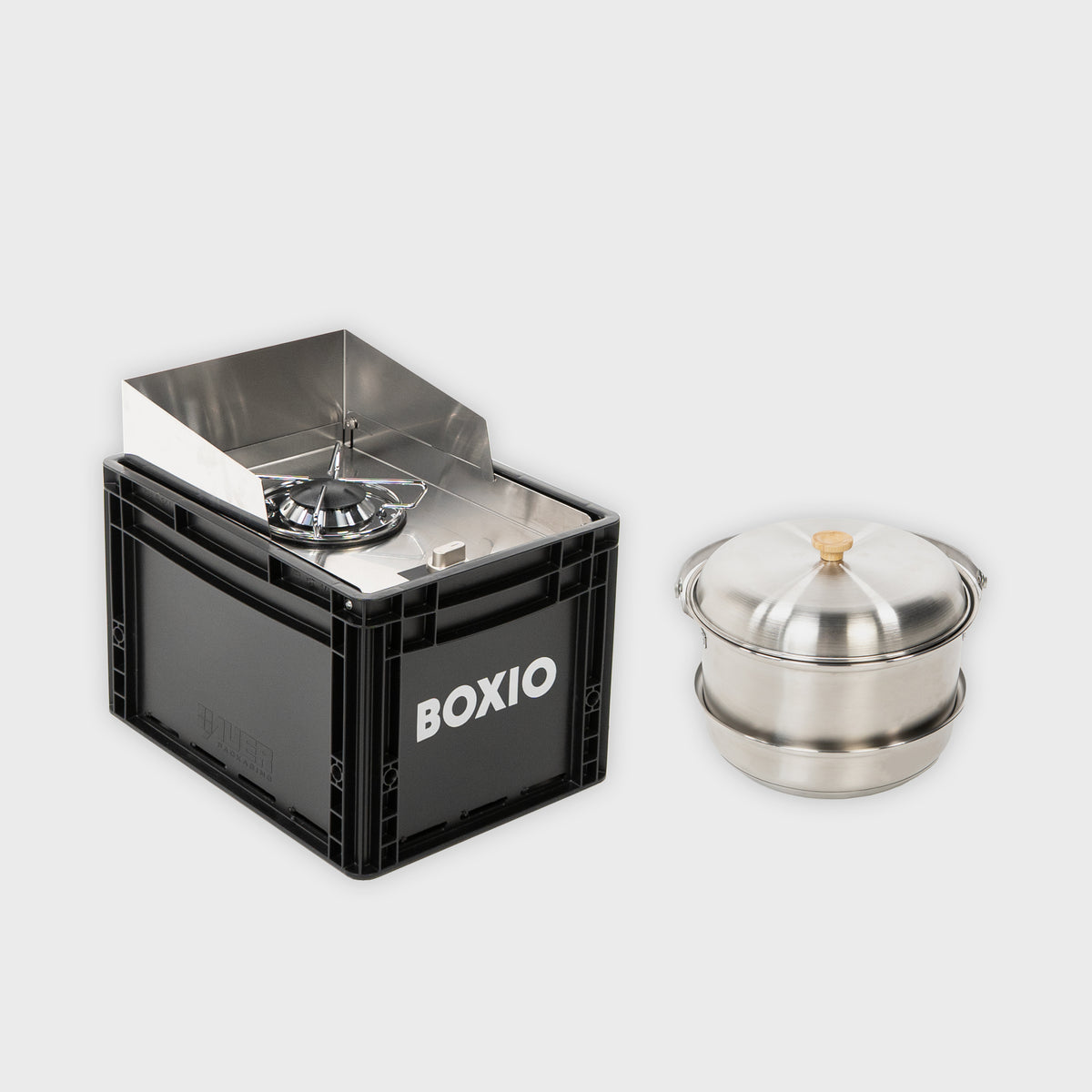 Tragbarer Campingkocher in schwarzer Box mit Edelstahl-Töpfen für Outdoor-Kochen.