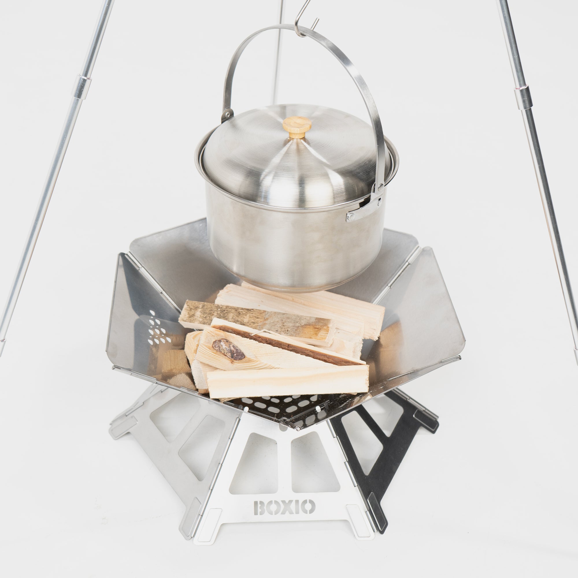 Edelstahl-Kochtopf auf einem stabilen Kocher mit Holzscheiten, ideal für Grillen und Camping.