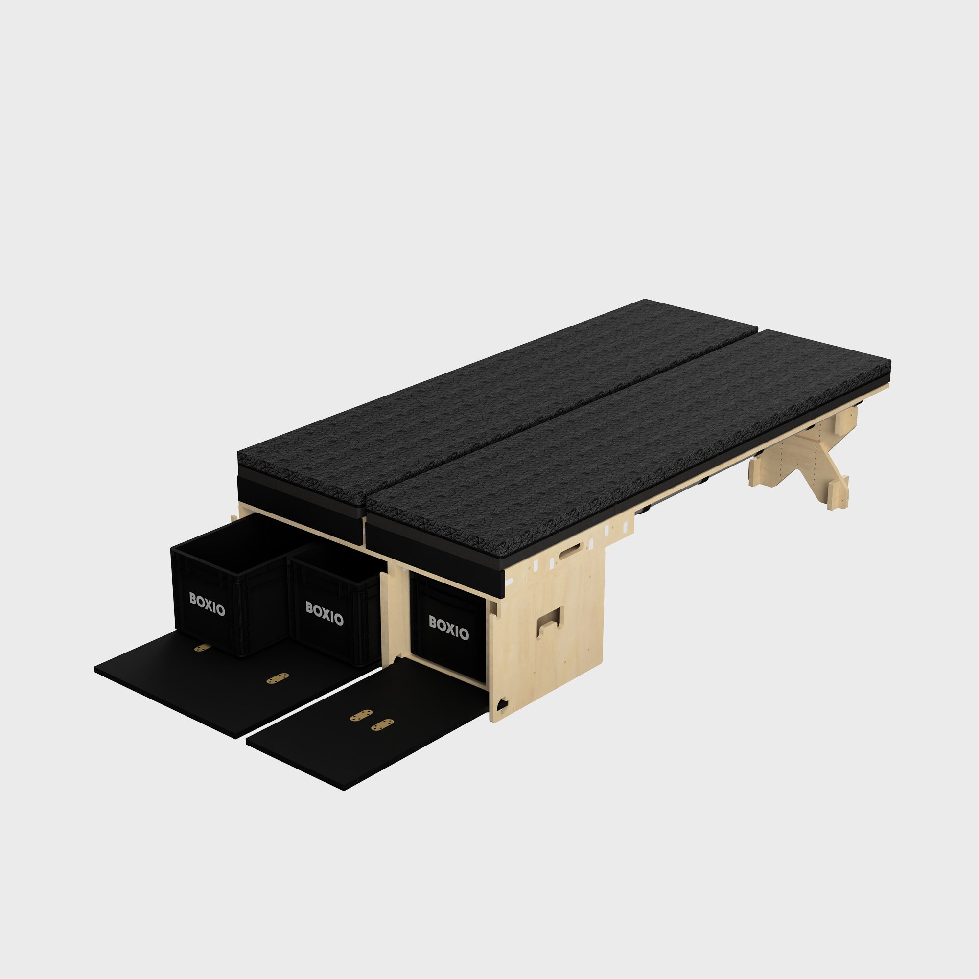 Modulares Möbelstück mit zwei schwarzen Matratzen, darunter Aufbewahrungskisten, aus Holz gefertigt. Ideal für Platzersparnis.