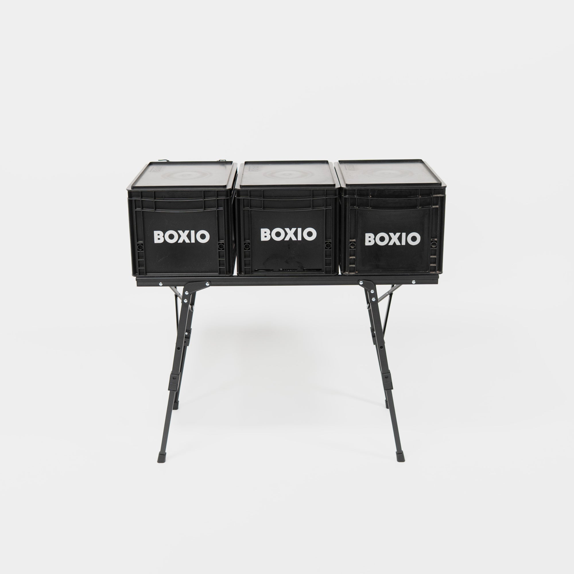 Stapelbare, schwarze Boxen mit der Aufschrift "BOXIO" auf einem stabilen, klappbaren Gestell.