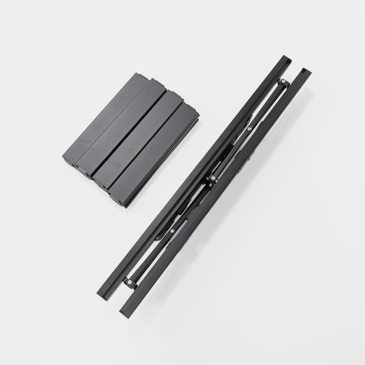 Faltbares schwarzes Aluminiumgestell und zusammengelegte Teile auf weißem Hintergrund. Ideal für mobile Anwendungen.