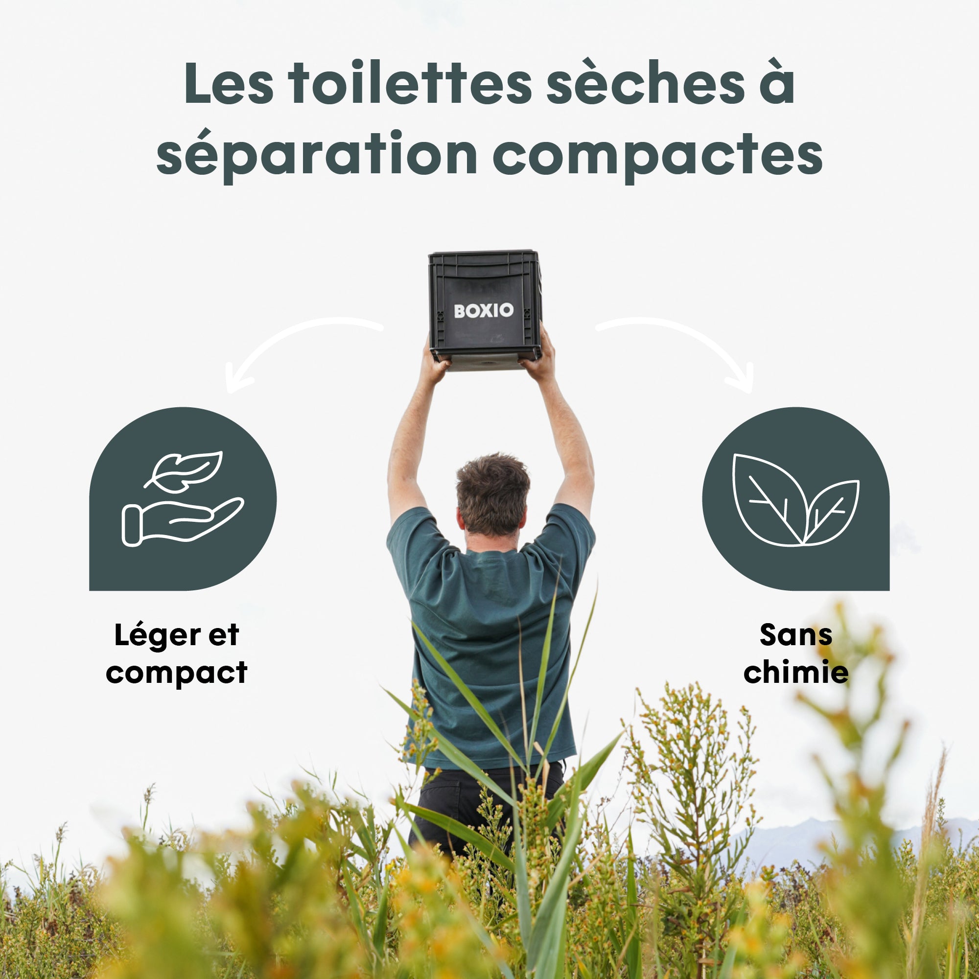 Mann hebt eine Box mit kompakten Trenn-Toiletten in einer grünen Landschaft in die Höhe.