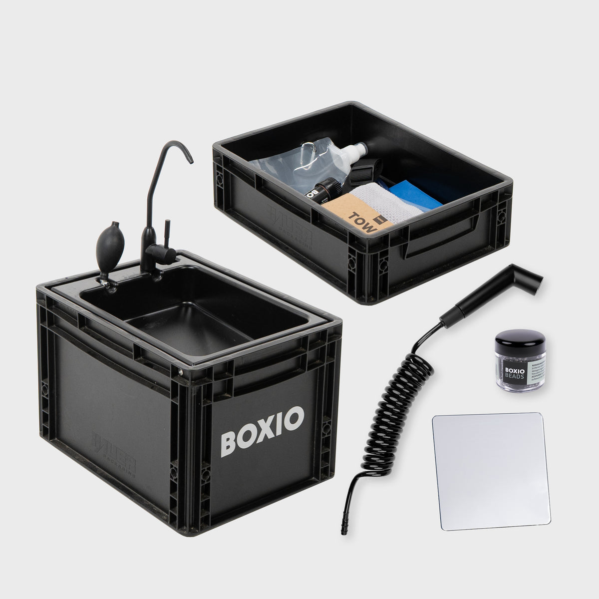 Praktische BOXIO-Waschanlage mit Zubehör: zwei schwarze Kisten, einem Schlauch und Reinigungsmitteln.