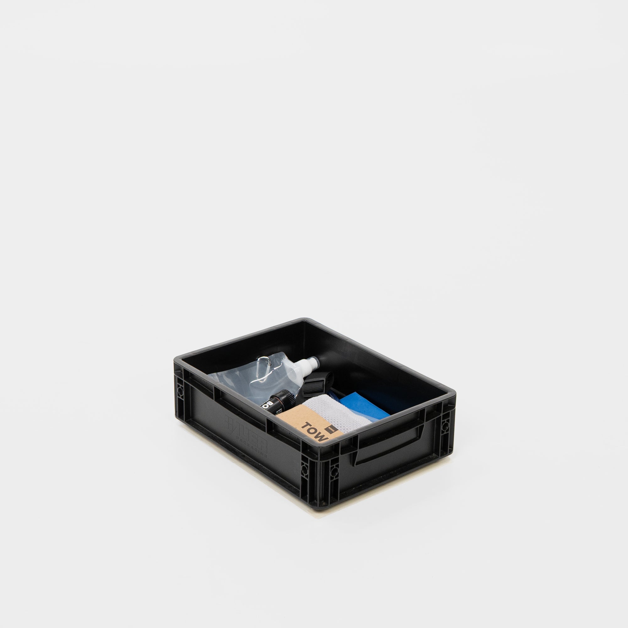 Schwarze Kunststoffbox mit Reinigungsmaterialien wie Sprühflasche, Tuch und Blöcken darin.
