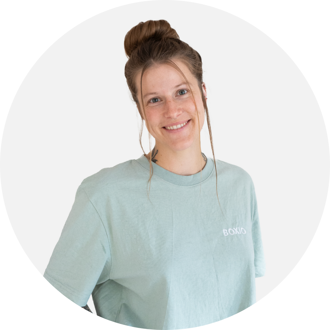 Junge Frau mit Zopf und freudigem Lächeln trägt ein mintgrünes T-Shirt, vor hellem Hintergrund.